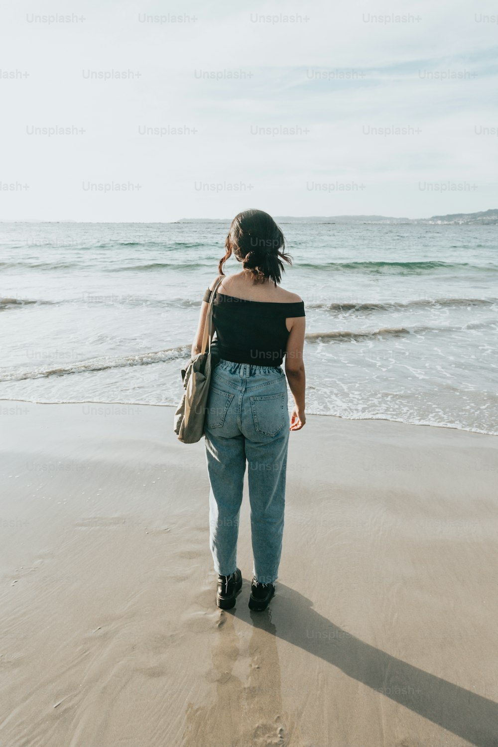 Una donna in piedi su una spiaggia vicino all'oceano