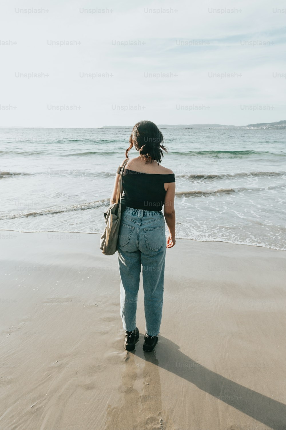 Une femme debout sur une plage au bord de l’océan