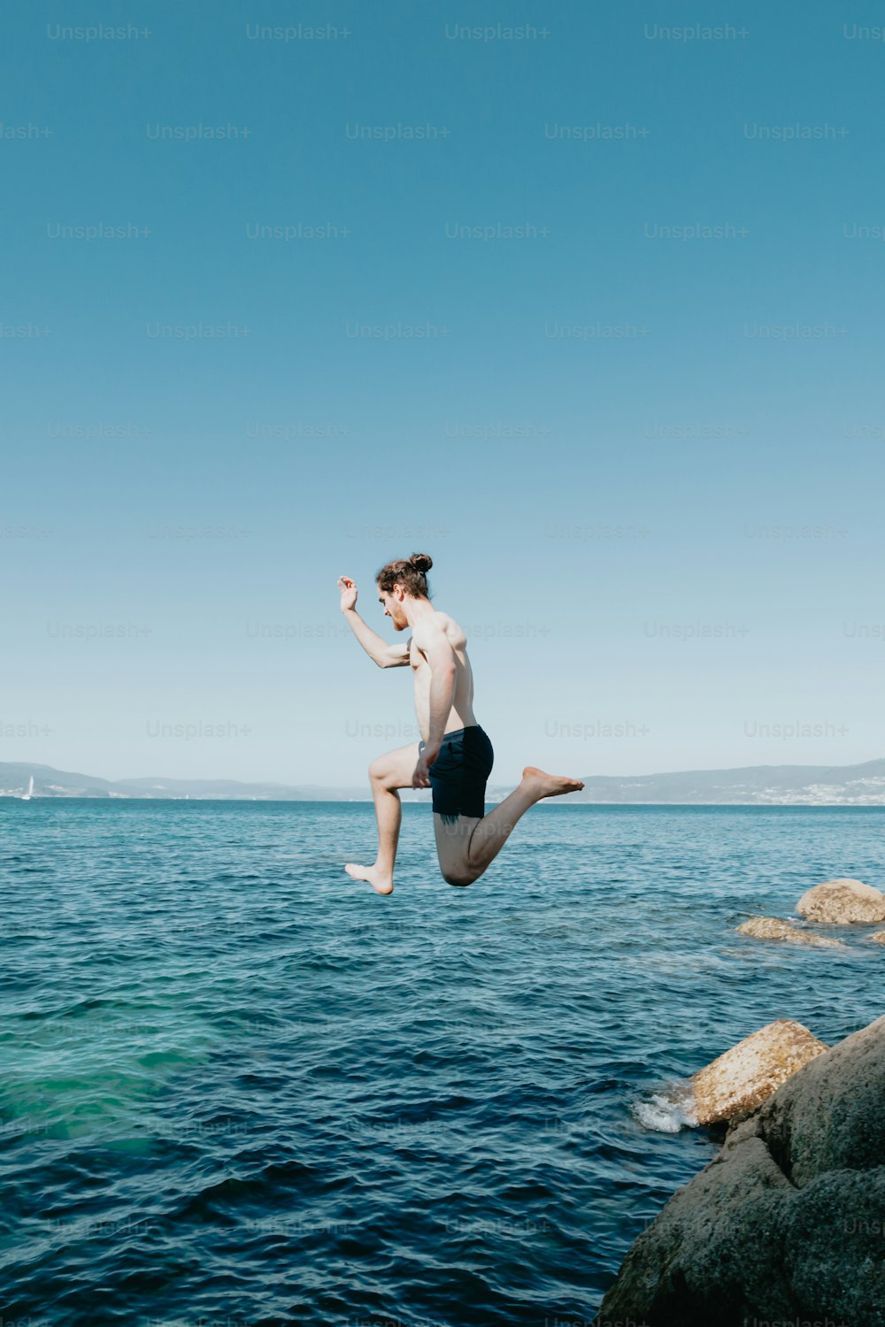 um homem pulando de um penhasco no oceano