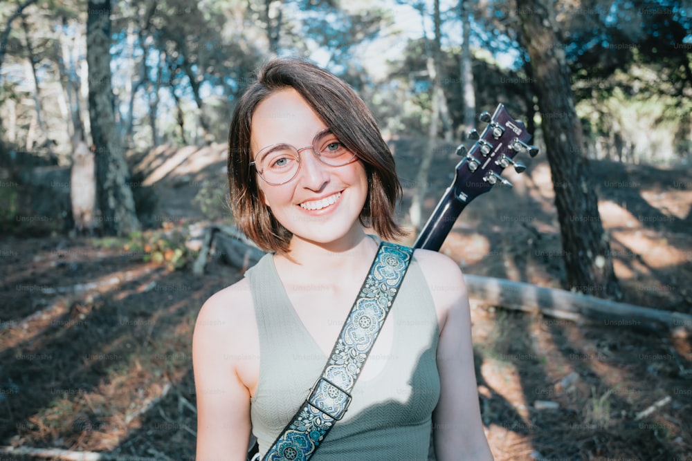 a woman holding a guitar in a forest