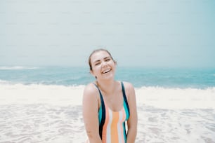 a woman in a striped bathing suit sitting on the beach