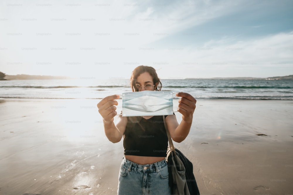una donna in piedi su una spiaggia con in mano un pezzo di carta