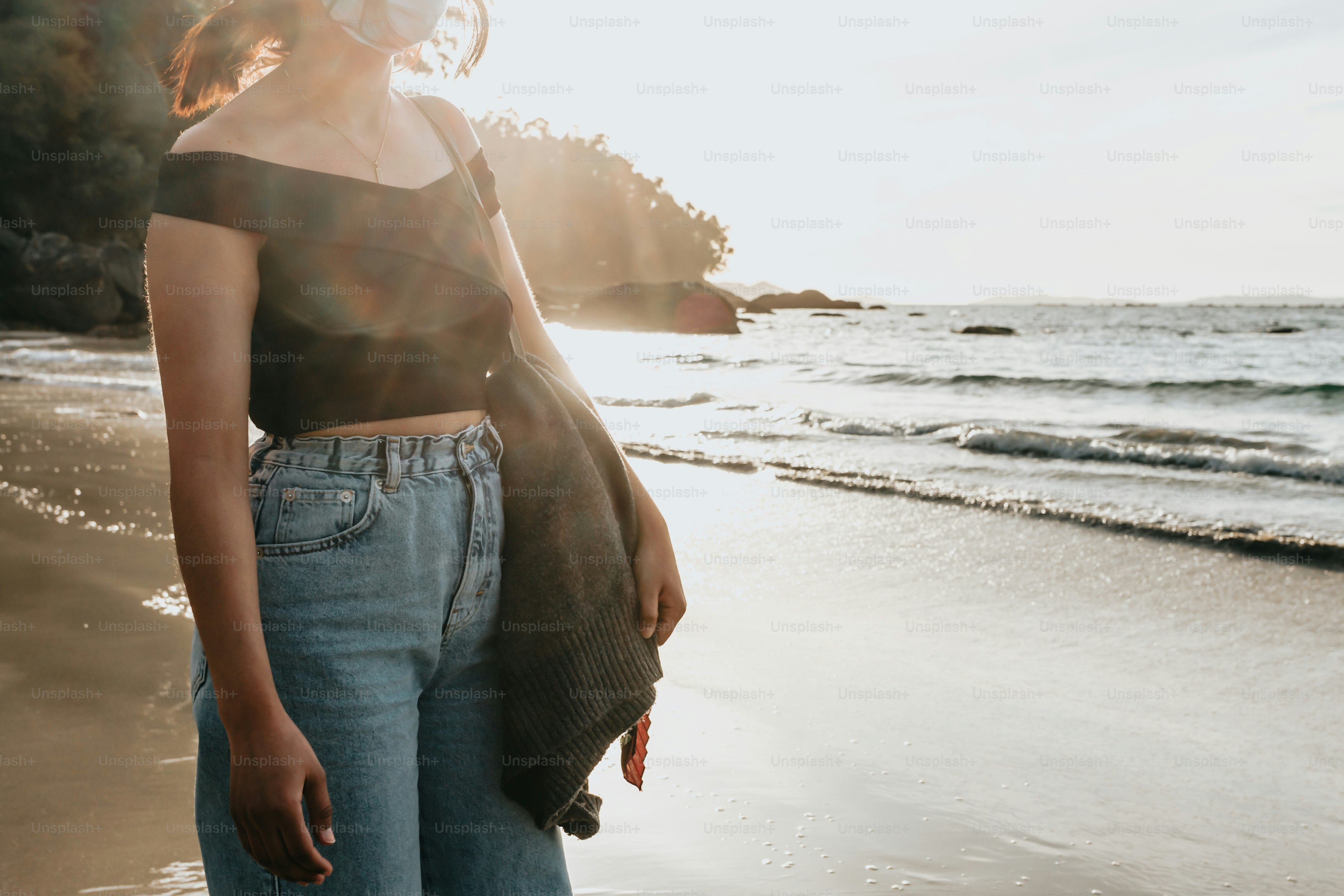 a woman standing on a beach next to the ocean