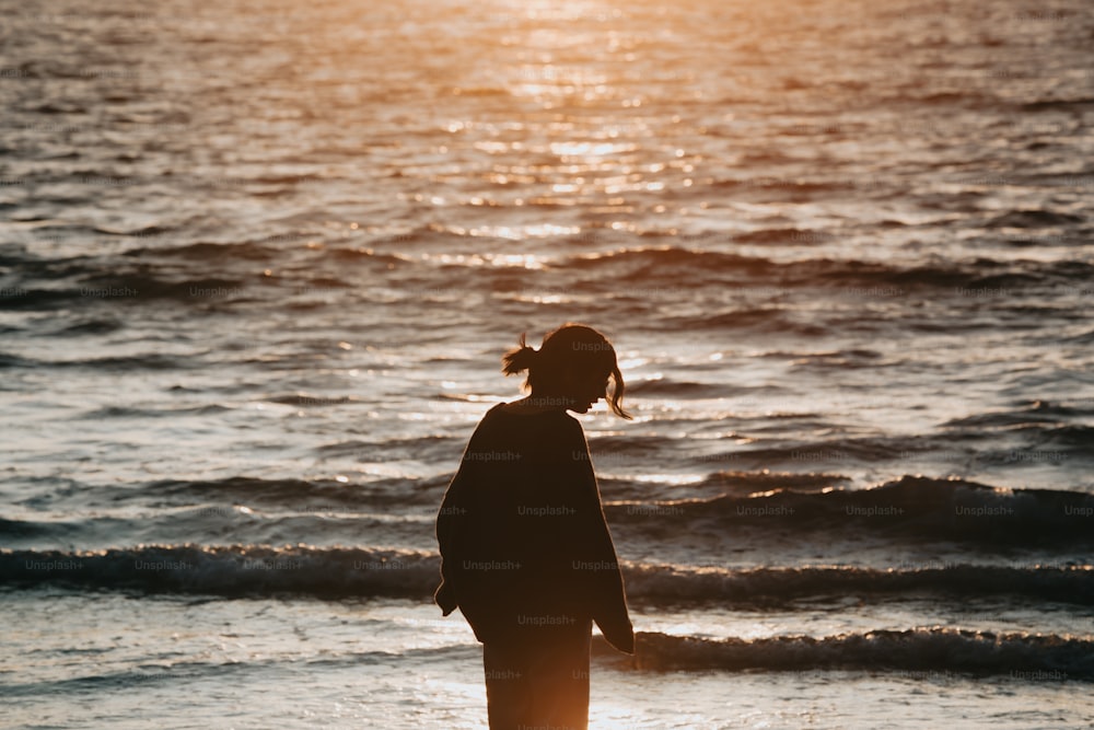 Una persona in piedi su una spiaggia vicino all'oceano