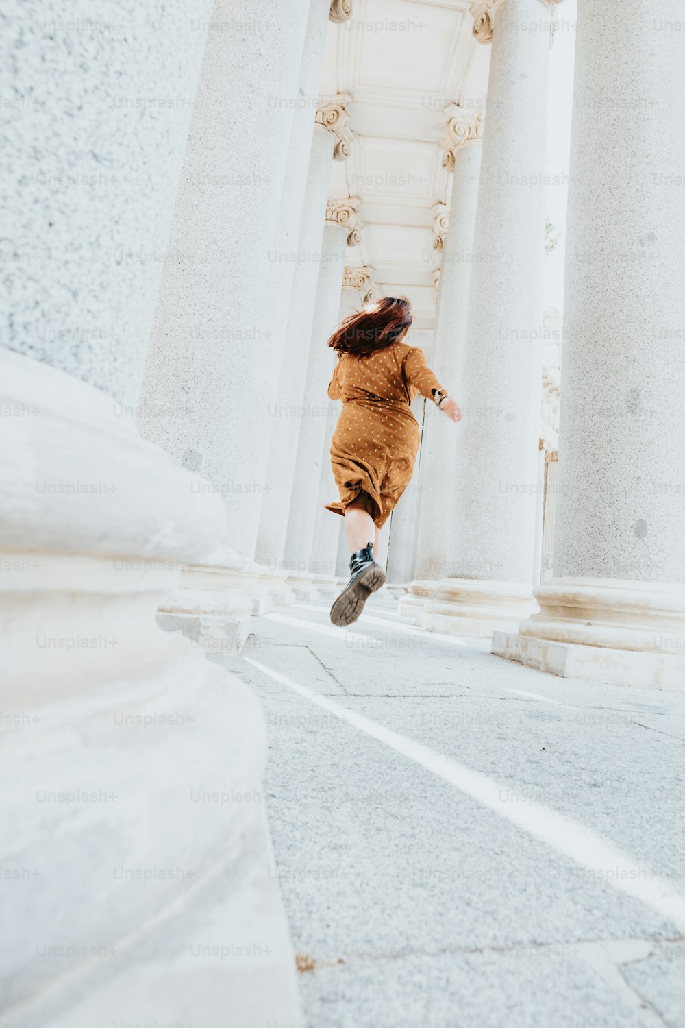 a woman in a brown dress is running down a street