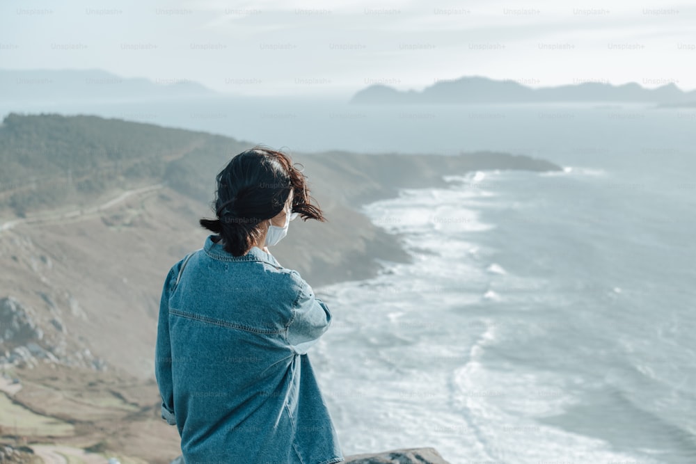 a woman standing on top of a cliff overlooking the ocean