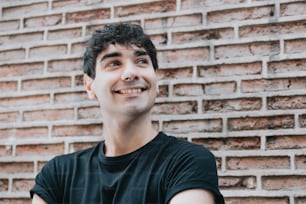 a man standing in front of a brick wall