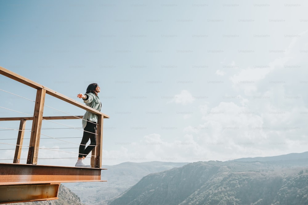 Una mujer está parada en un balcón con vistas a las montañas