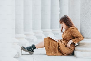 a woman sitting on the ground reading a book