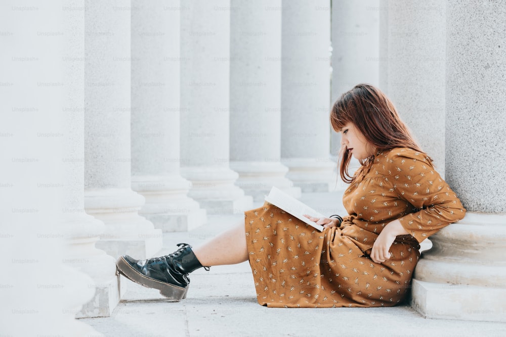 한 여자가 바닥에 앉아 책을 읽고 있다