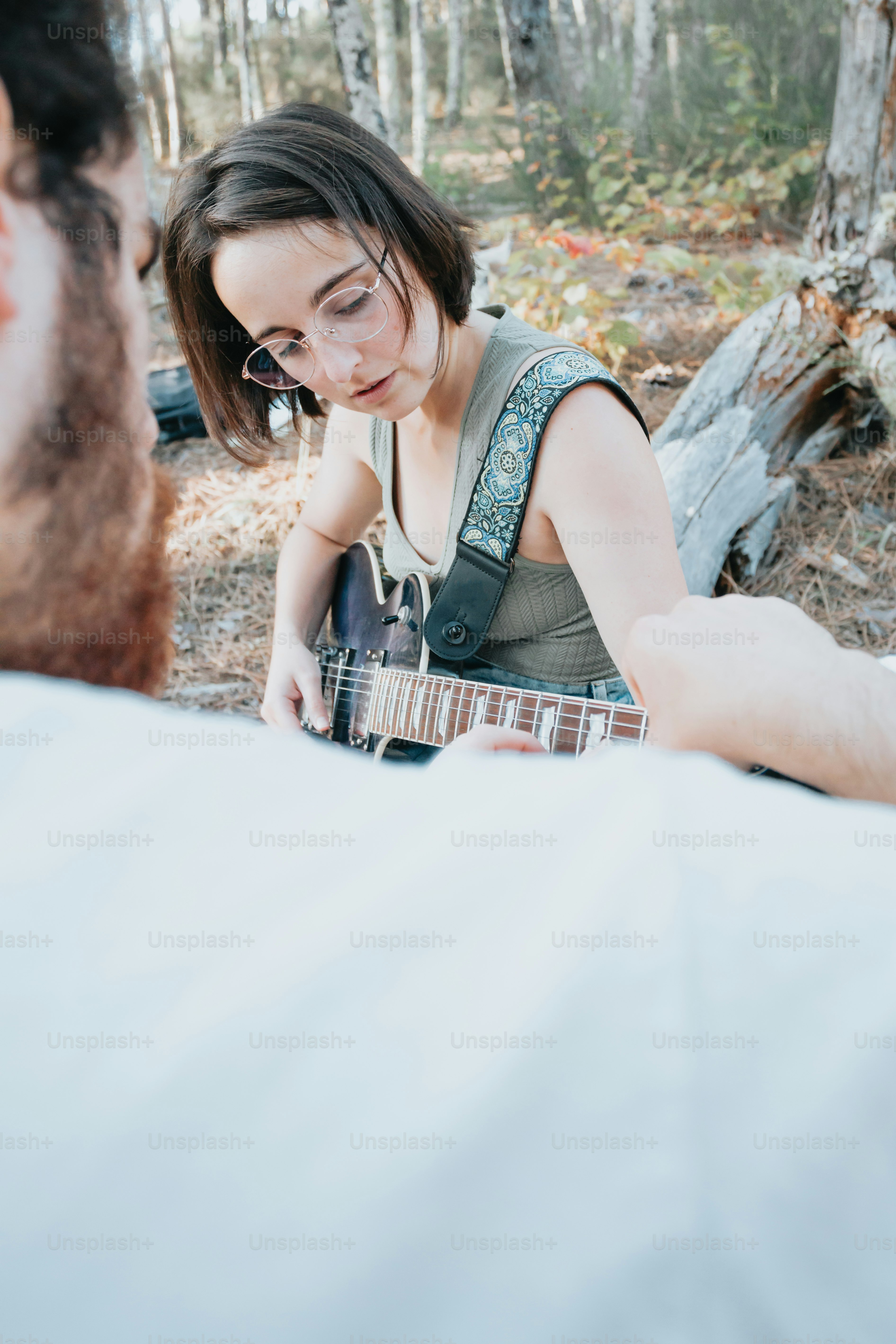 a woman playing a guitar in the woods