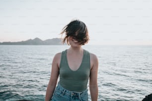 a woman standing on a rocky beach next to the ocean