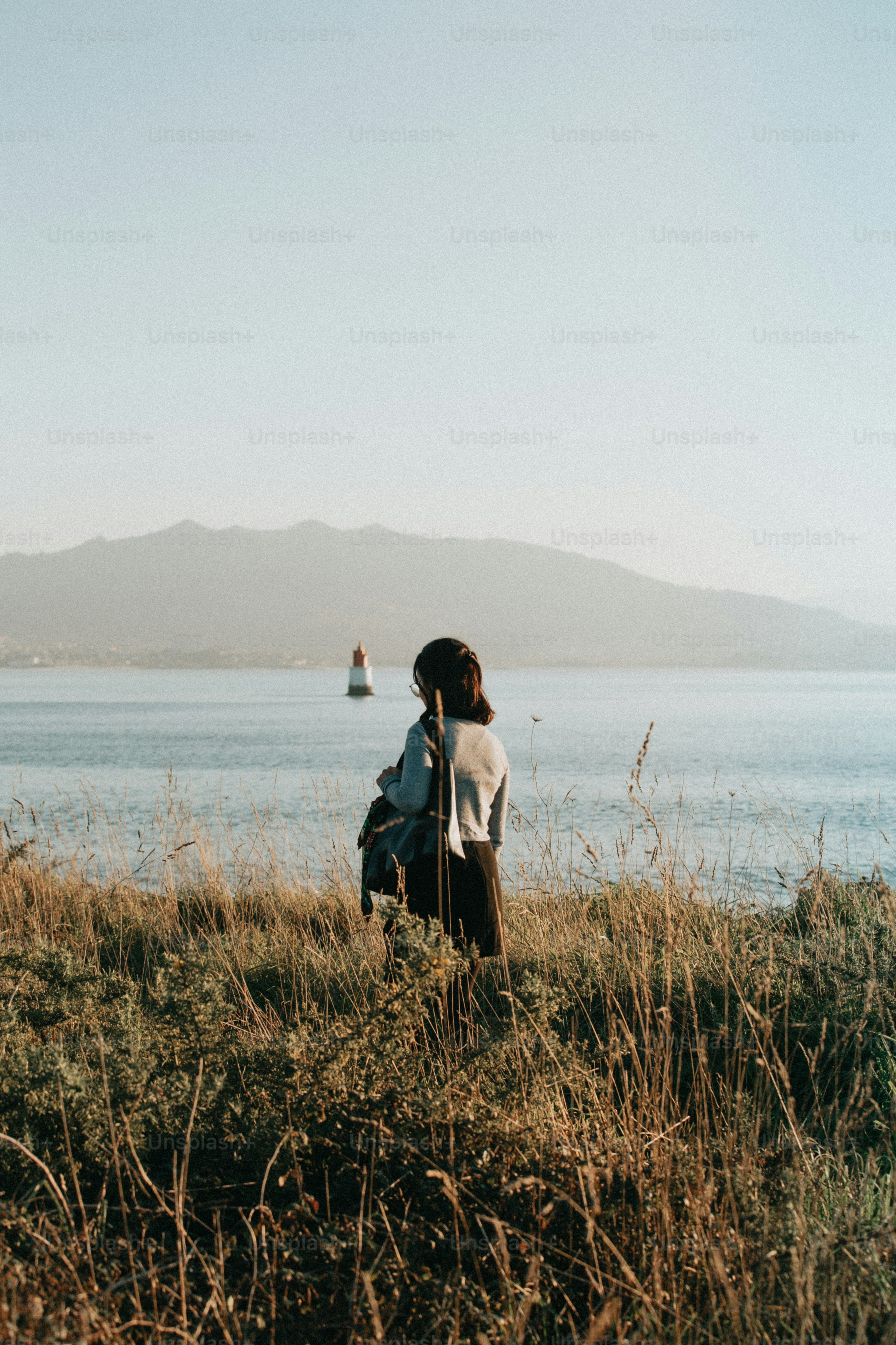 a person sitting on a hill overlooking a body of water