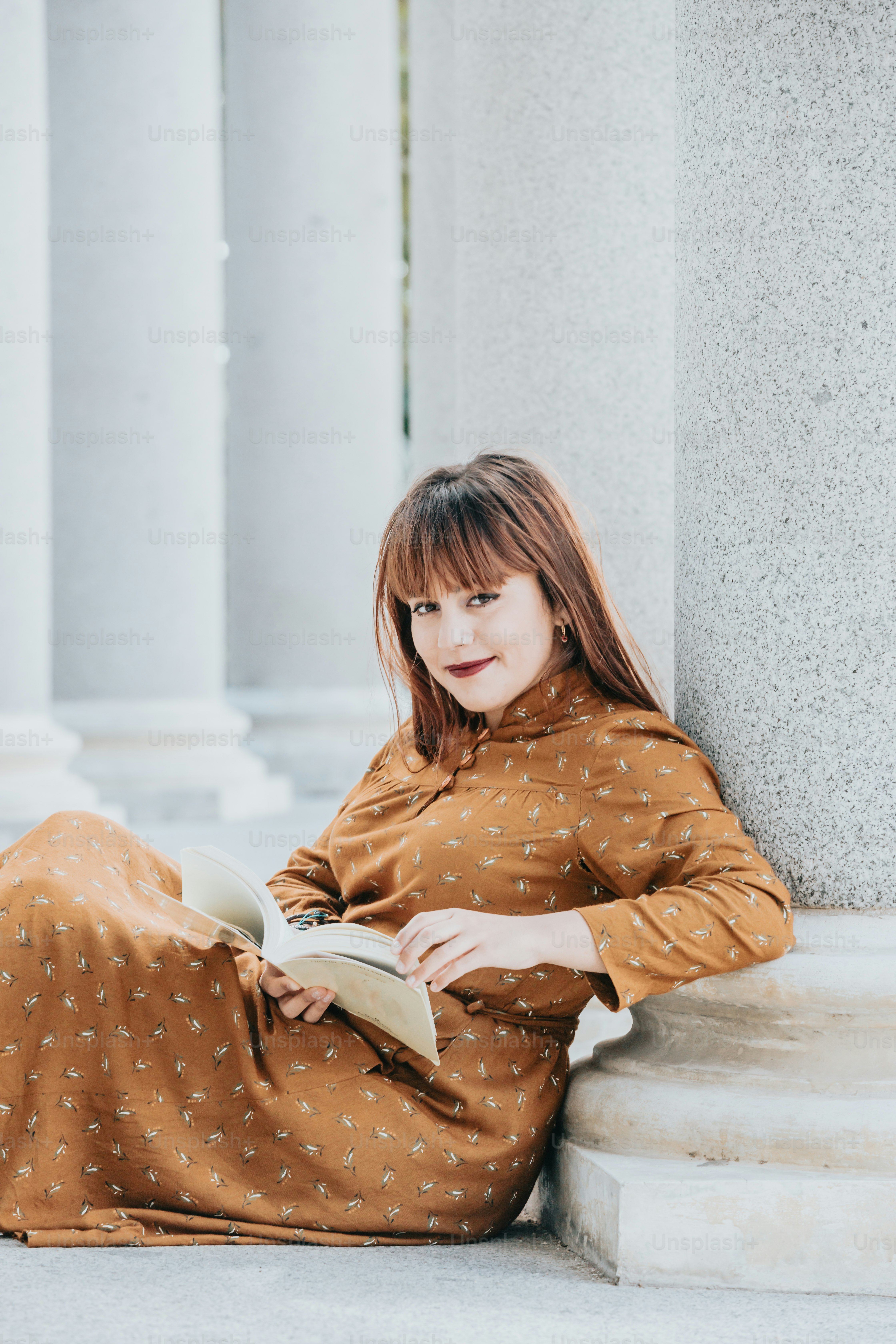 une femme assise par terre en train de lire un livre