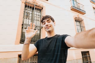 a man holding up a peace sign in front of a building
