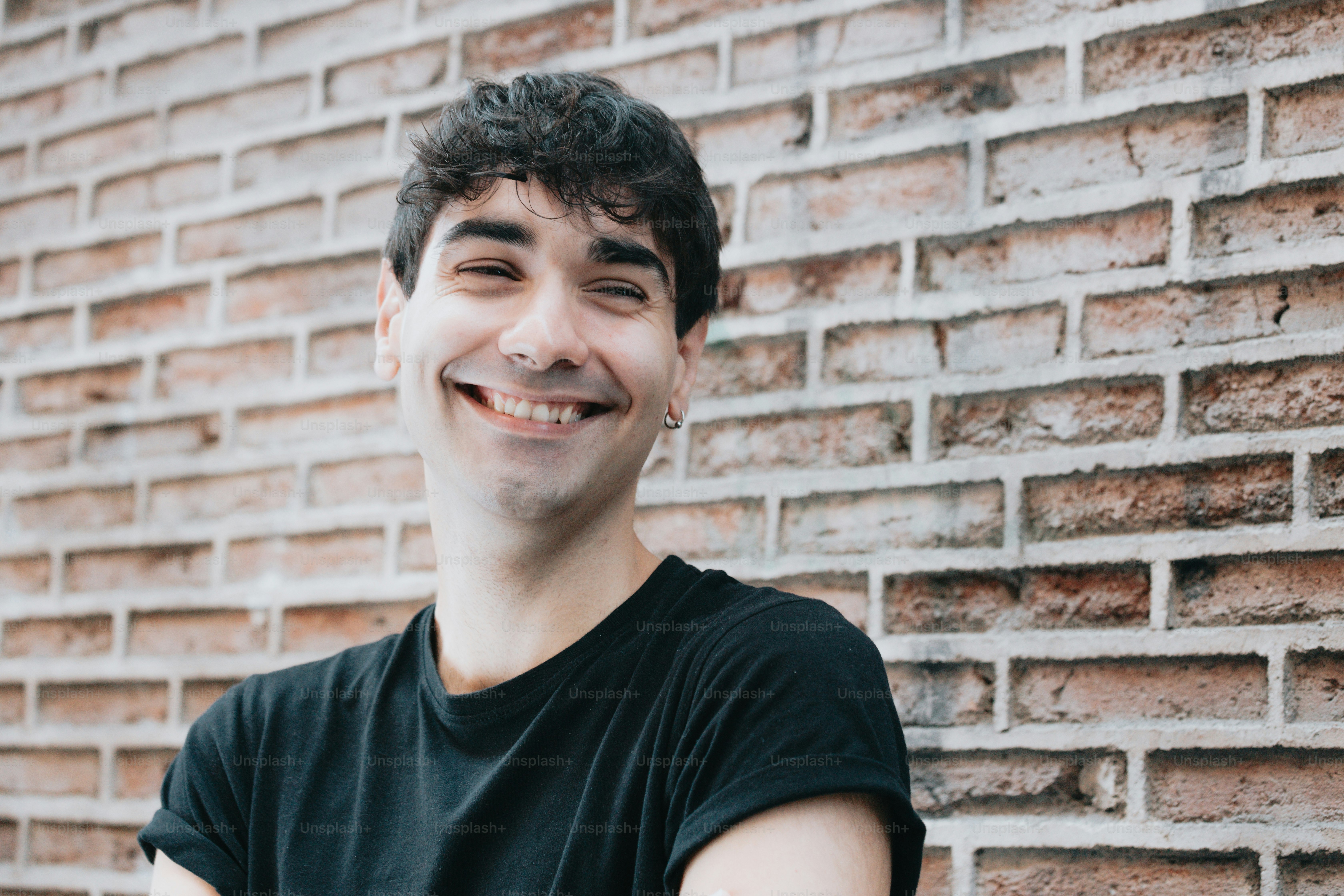 A man standing in front of a brick wall photo – Happy Image on Unsplash