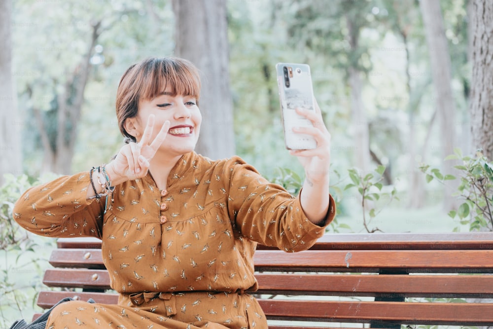 a woman sitting on a bench taking a selfie with her phone