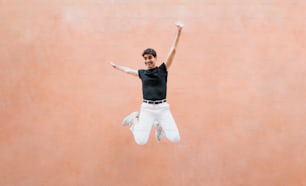 Un hombre con camisa negra y pantalones blancos saltando en el aire