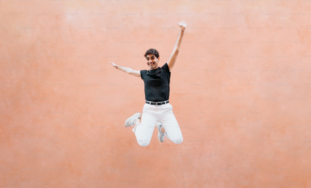 a man in black shirt and white pants jumping in the air