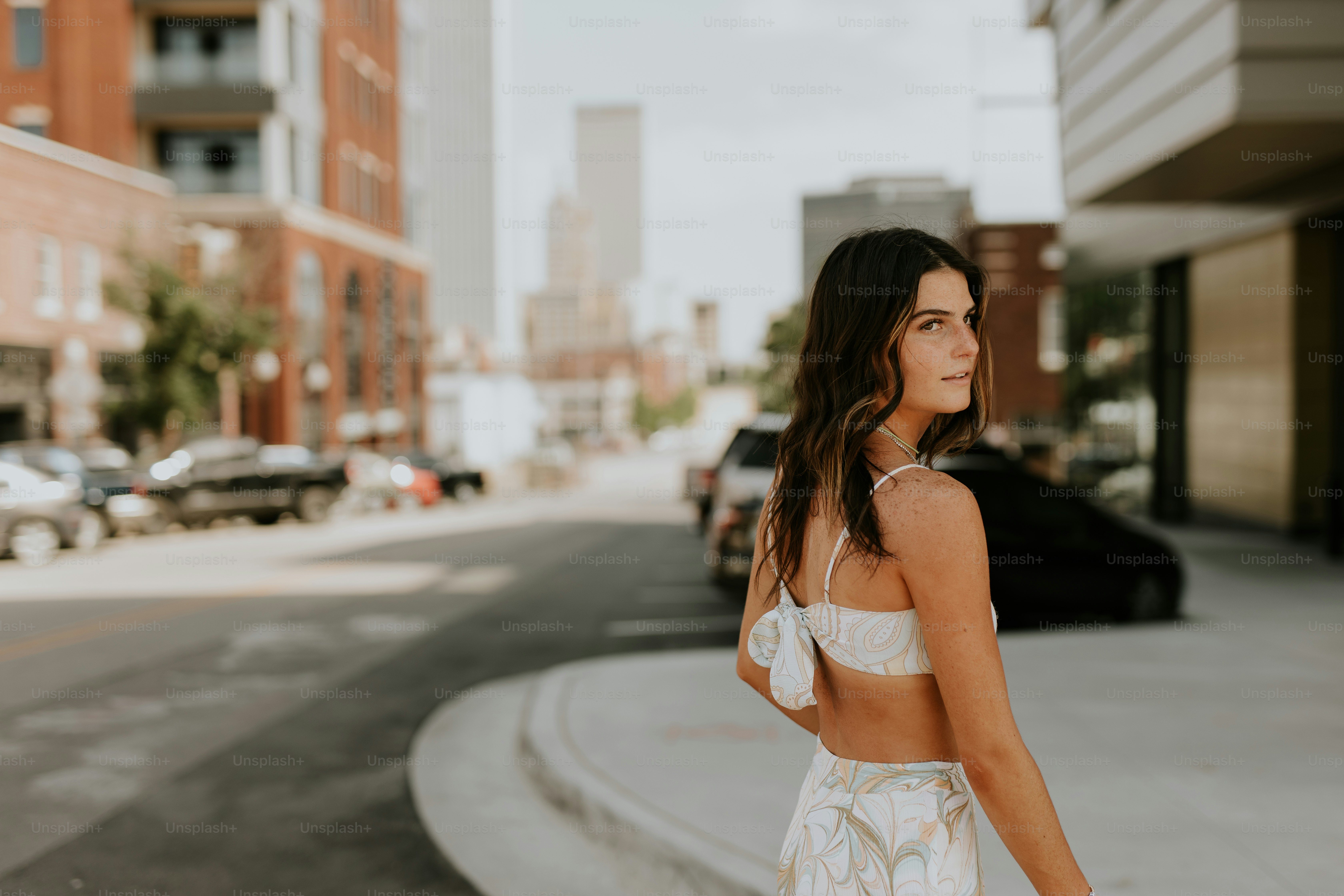 uma mulher andando por uma rua ao lado de edifícios altos