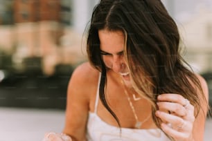 a woman in a white tank top holding a cell phone