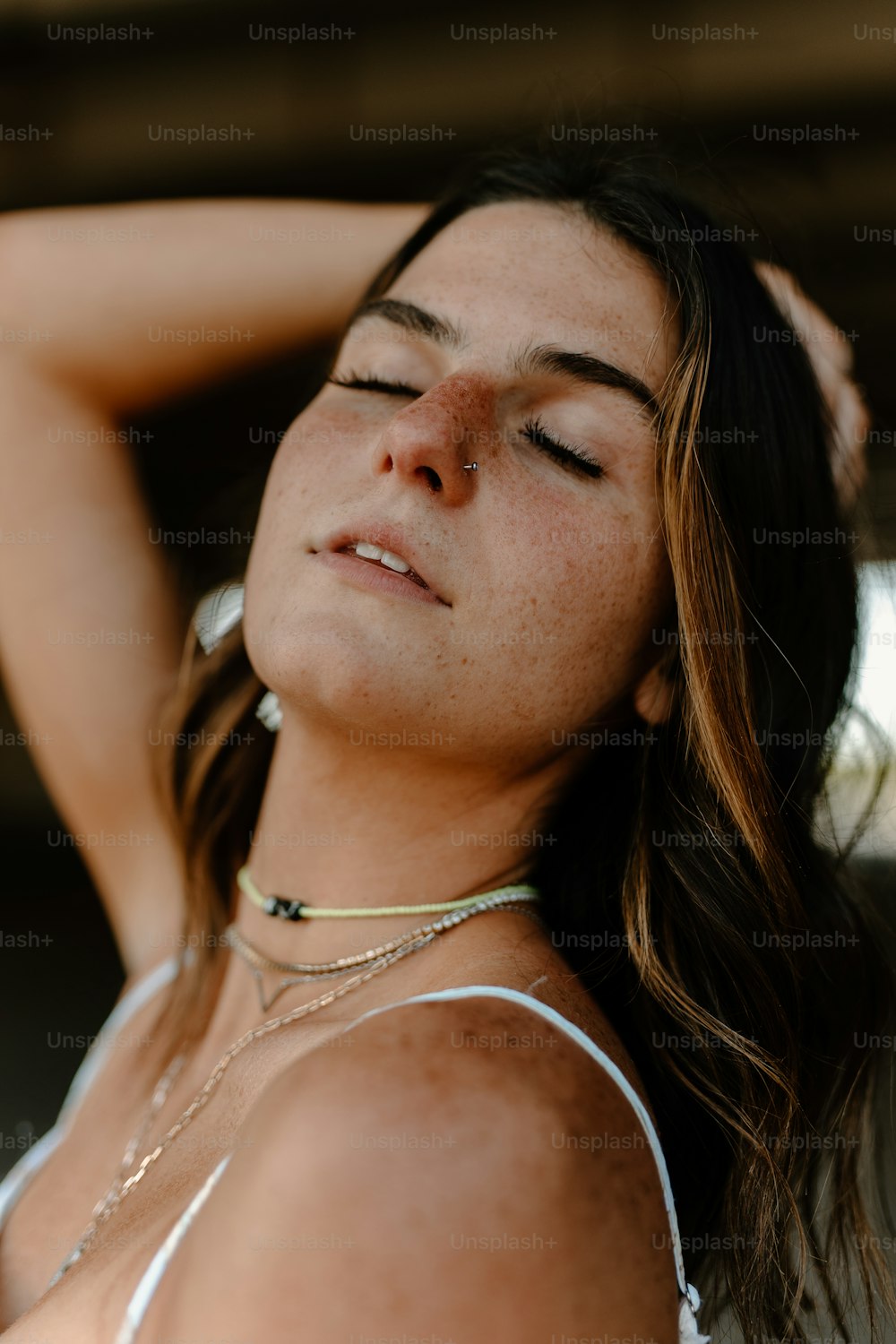 a woman with her eyes closed wearing a necklace