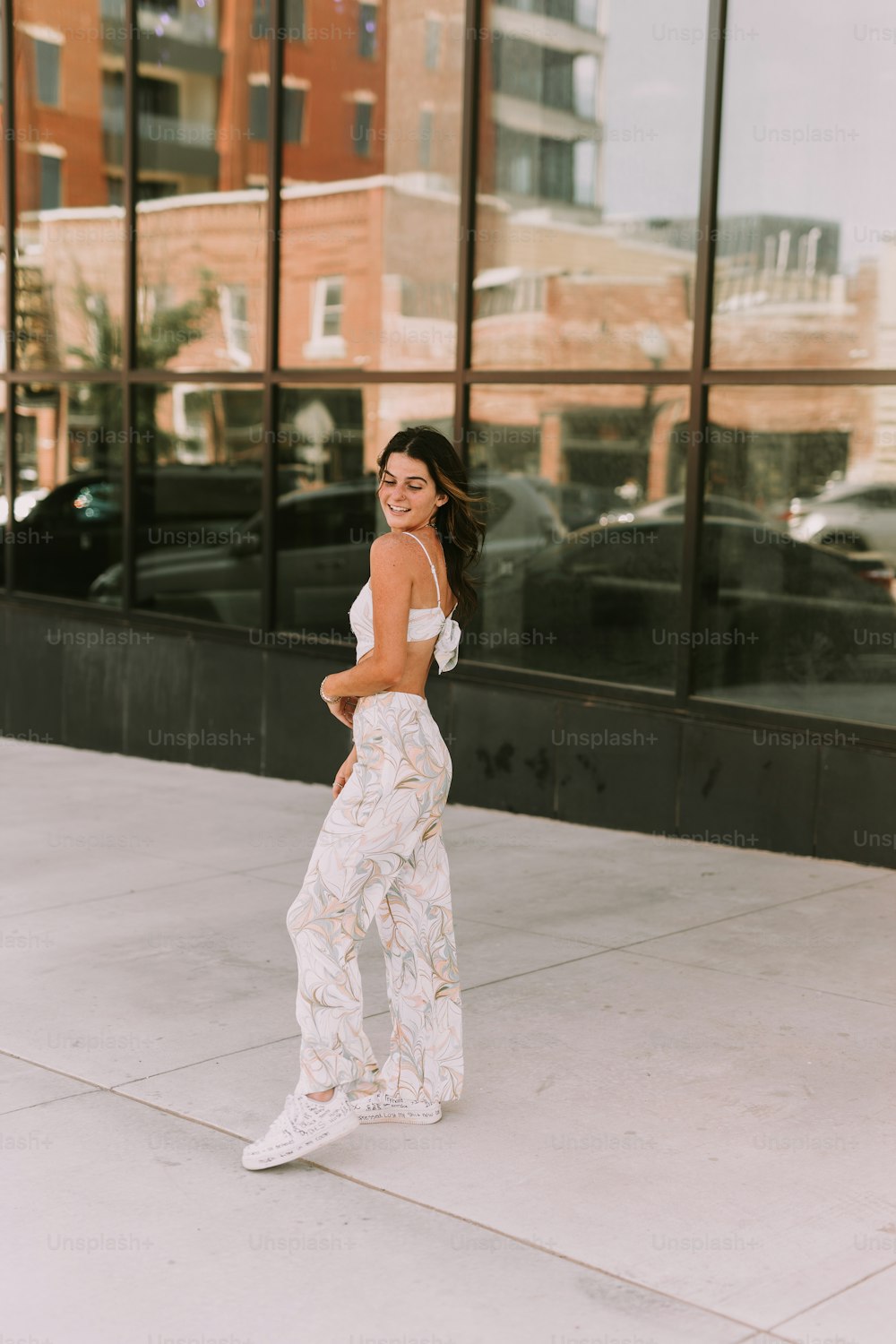 a woman standing on a sidewalk in front of a building