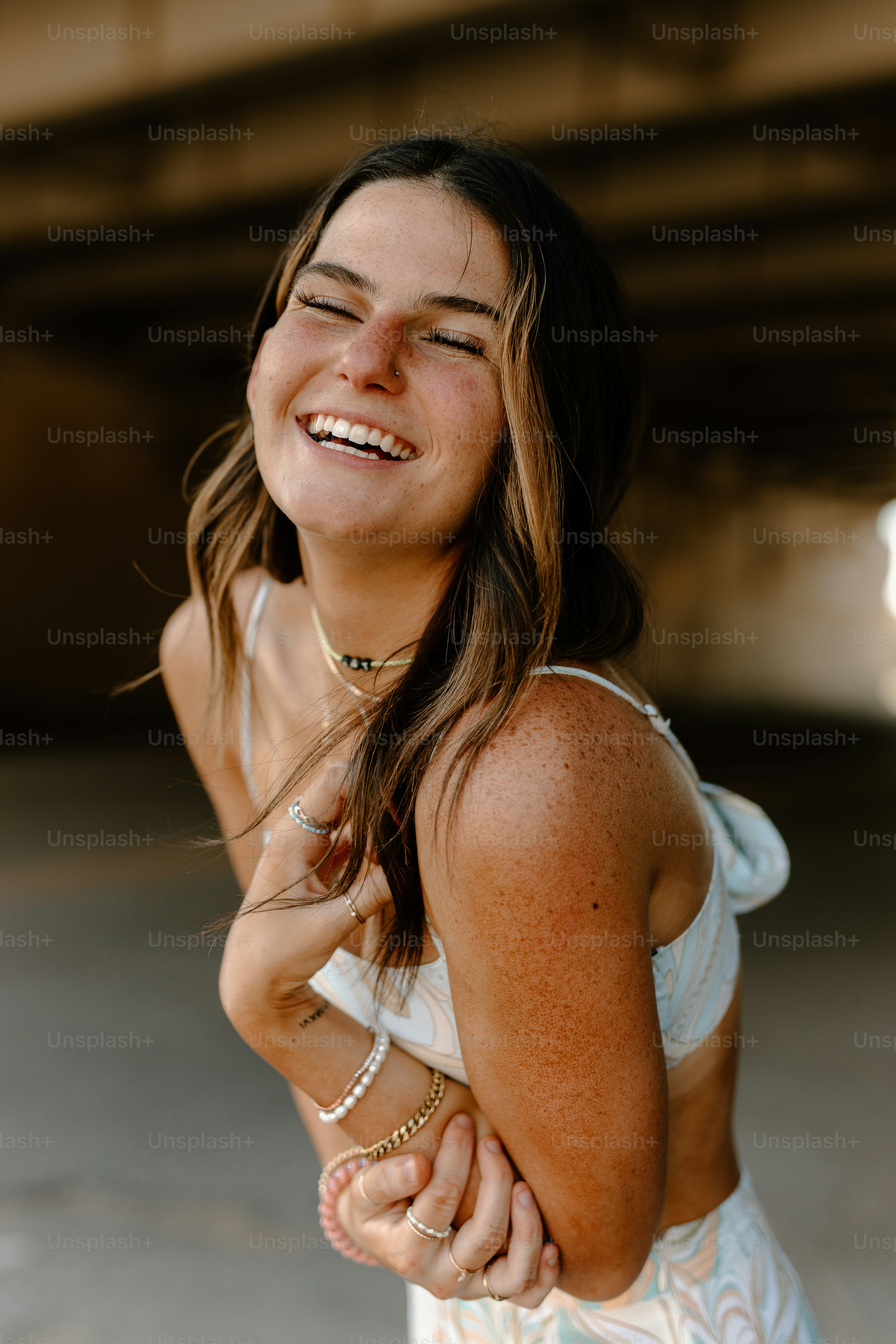 a smiling woman in a white dress holding her hands together