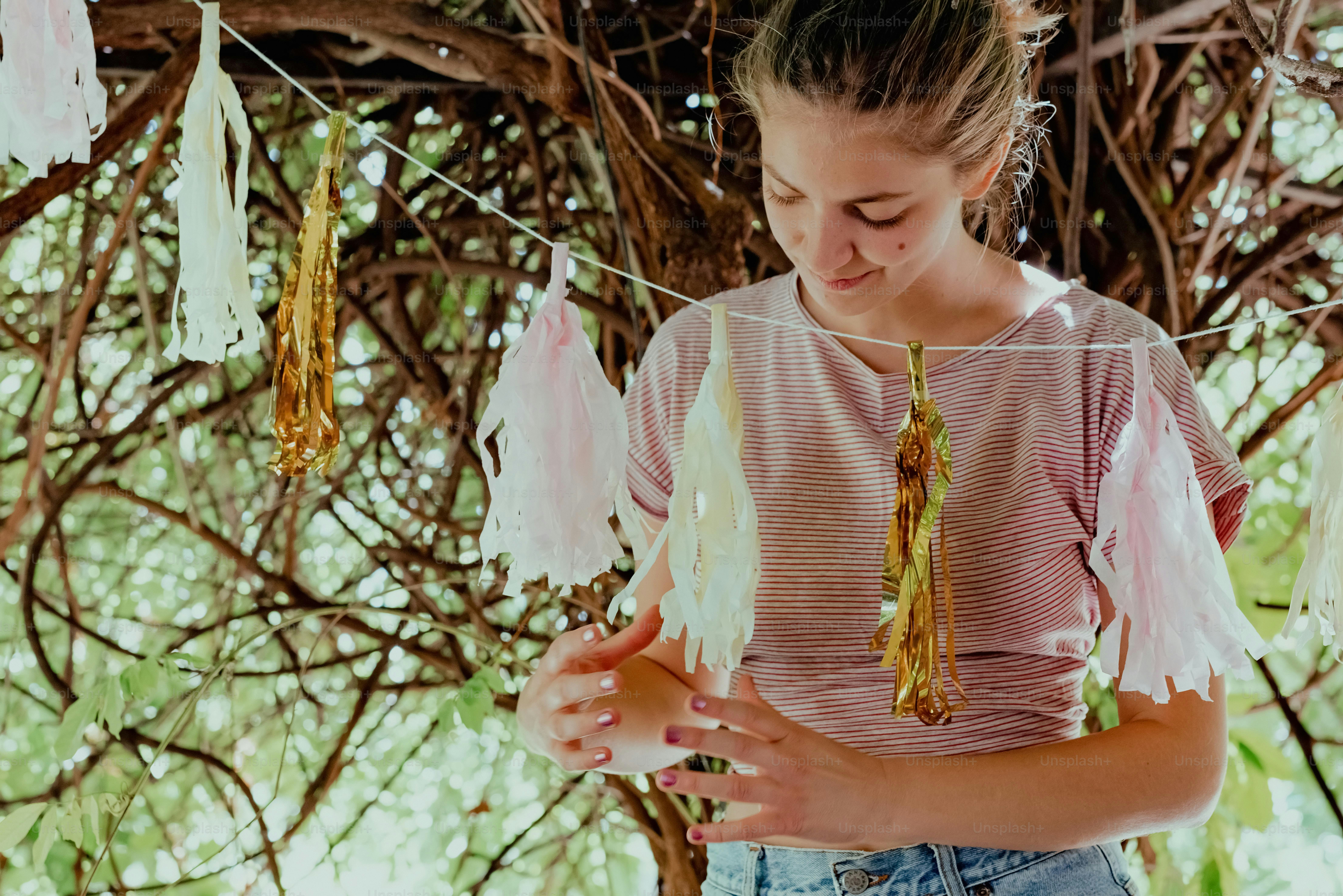 a girl is standing under a tree and looking at her cell phone