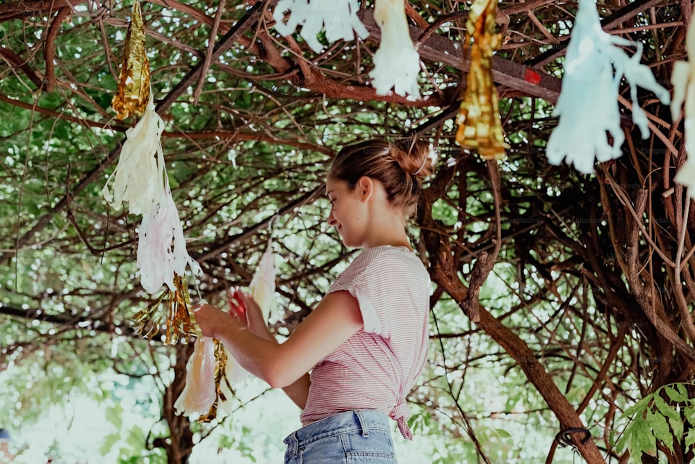 uma jovem em pé sob uma árvore segurando um pedaço de papel