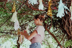 a young girl standing under a tree holding a piece of paper