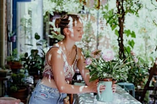 a woman holding a potted plant on a table