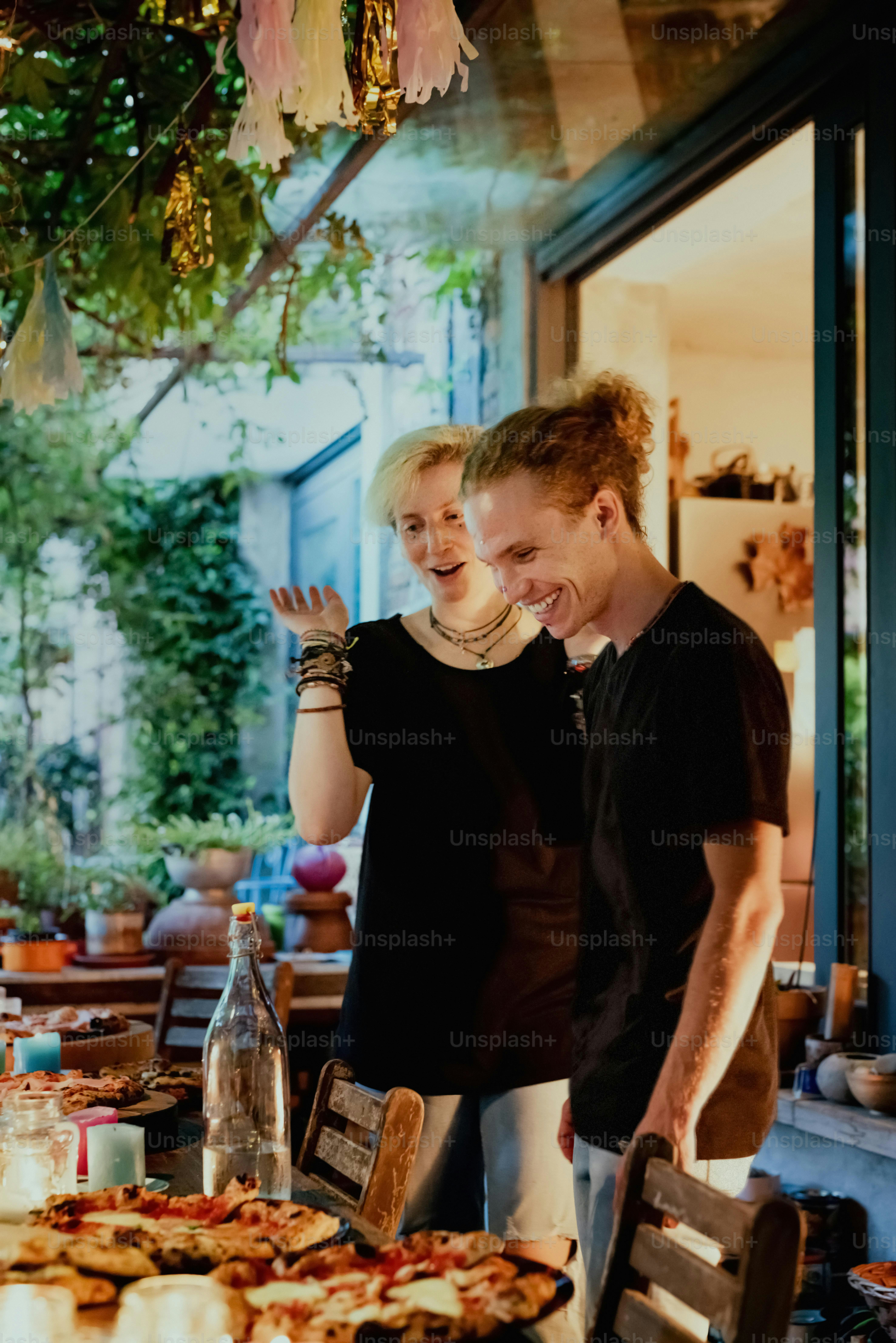 a man and a woman standing in front of a pizza