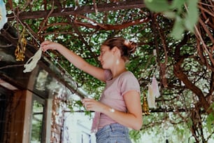 a woman is hanging decorations from a tree