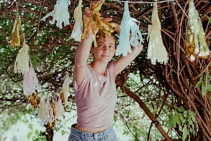 a young girl standing under a tree with a bunch of tassels hanging from