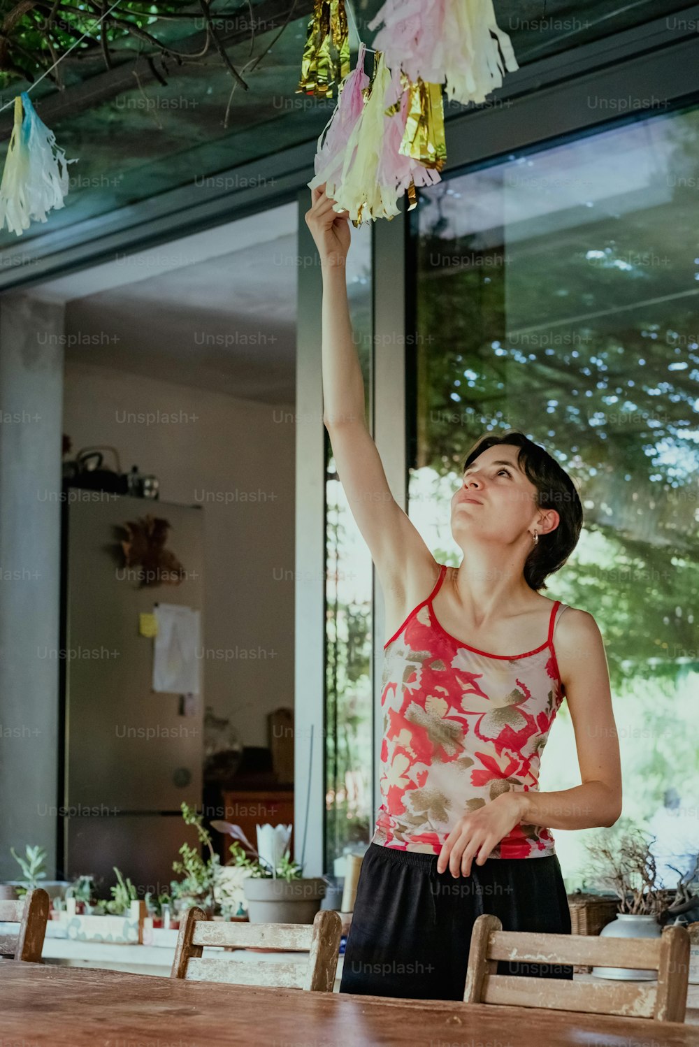 a woman reaching up to a string of flowers