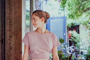 a woman standing in front of a window next to a potted plant