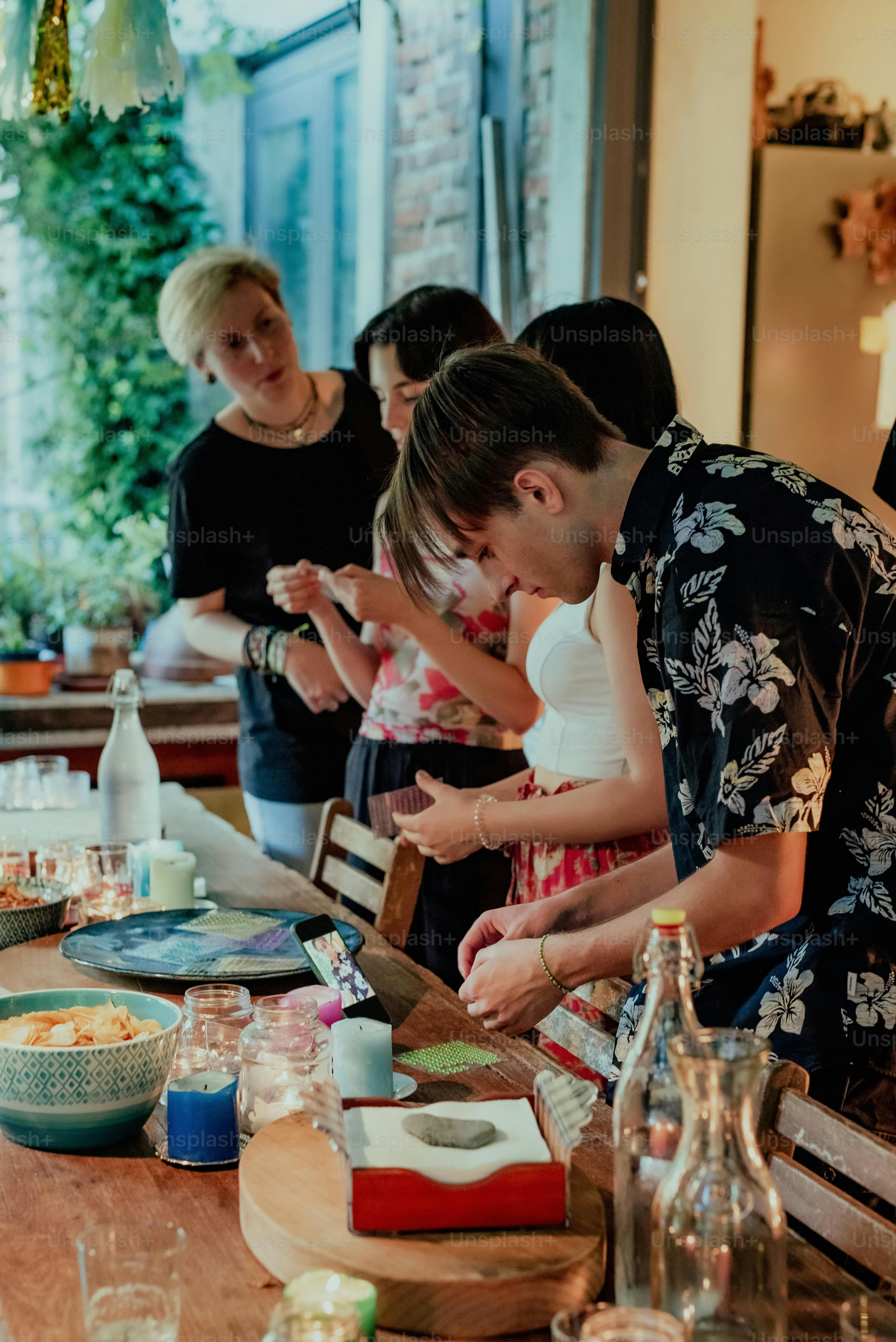 A group of people sitting around a table with food photo – Food Image ...