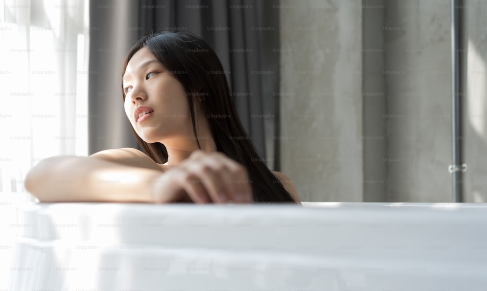 Young Asian woman relaxing in a bath . Female skincare concept