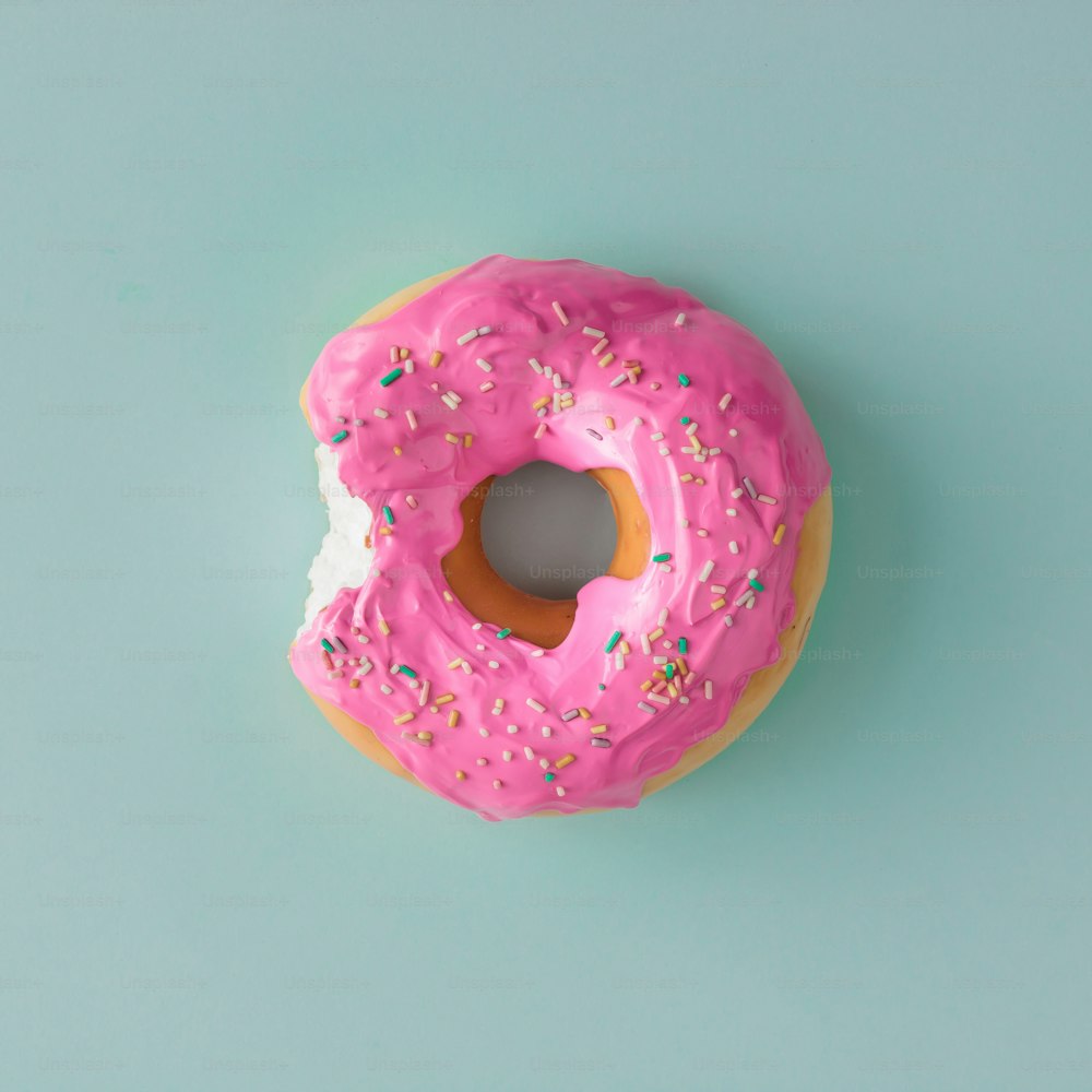 Pink glazed donut on blue pastel background. Flat lay. Creative concept.