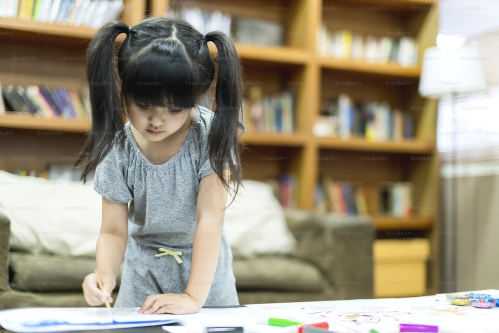 cute daughter focus on painting crayon with concentrate in living room home concept