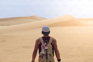 Guy young man alone with a travel backpack in a desert background.