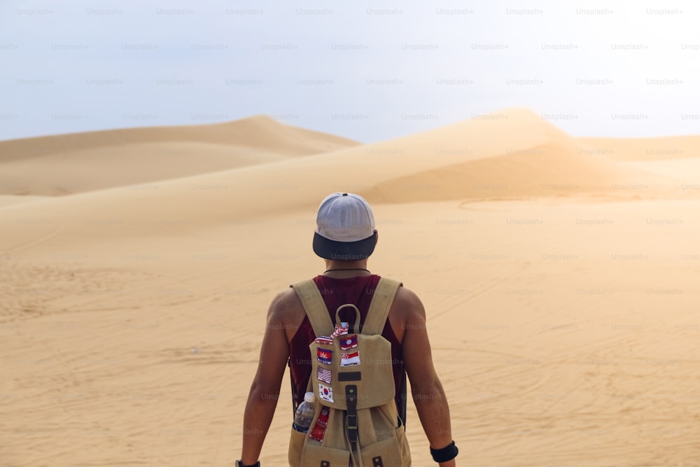 Guy young man alone with a travel backpack in a desert background.