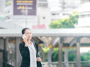Portrait of cheerful young woman talking on smartphone and laughing outdoors. Happy beautiful caucasian business woman using mobile phone, making call on the street in city. Copy space