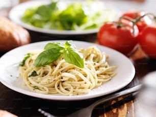 Foto de un plato de espaguetis italianos con salsa pesto tomada con enfoque selectivo