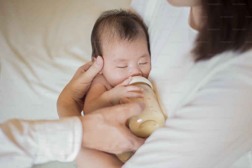 生まれたばかりの女の赤ちゃんが母親にミルクを飲んでいる