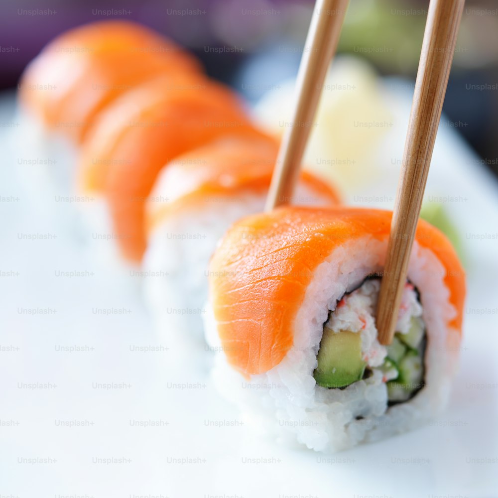 Prendere un pezzo di sushi di salmone con le bacchette