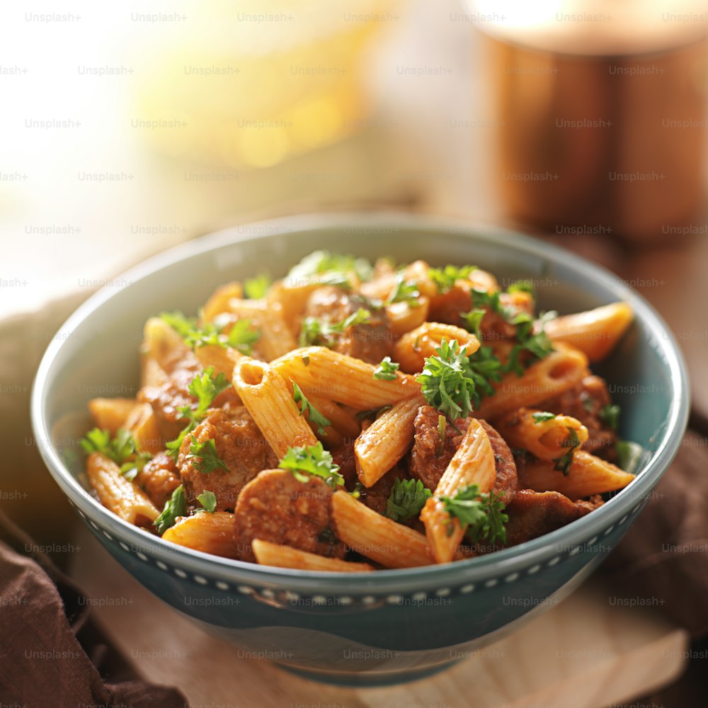 close up photo of a bowl of rigatoni pasta with sausage shot with extreme selective focus.