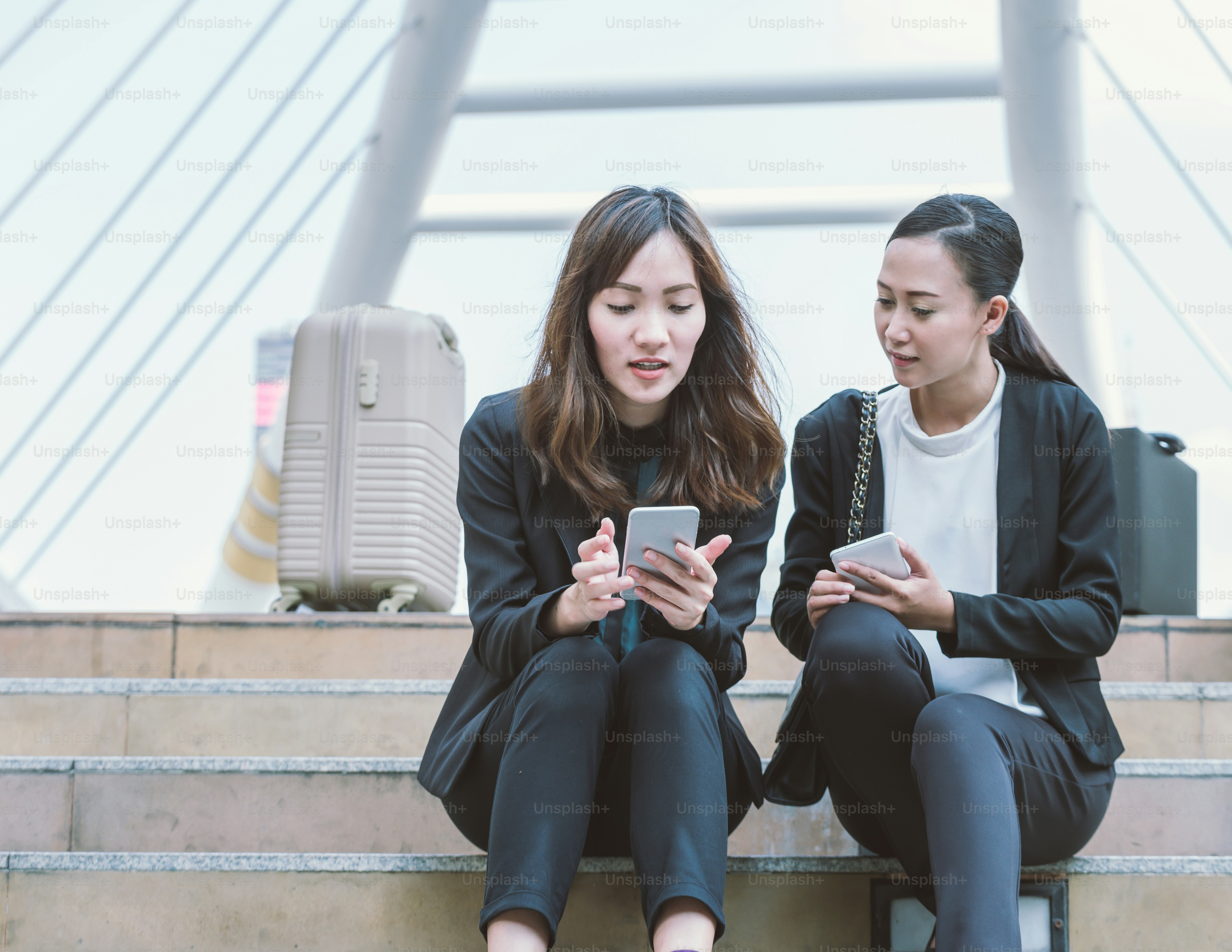 Two businesswomen talking about smart phone in the street with office buildings in the background