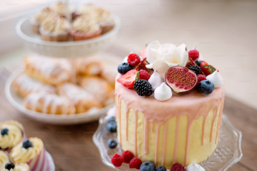 Kuchen mit verschiedenen Beeren und Baisern auf einem Stand. Cupcakes und Tuben mit Pastete auf anderem Stand. Studioaufnahme.